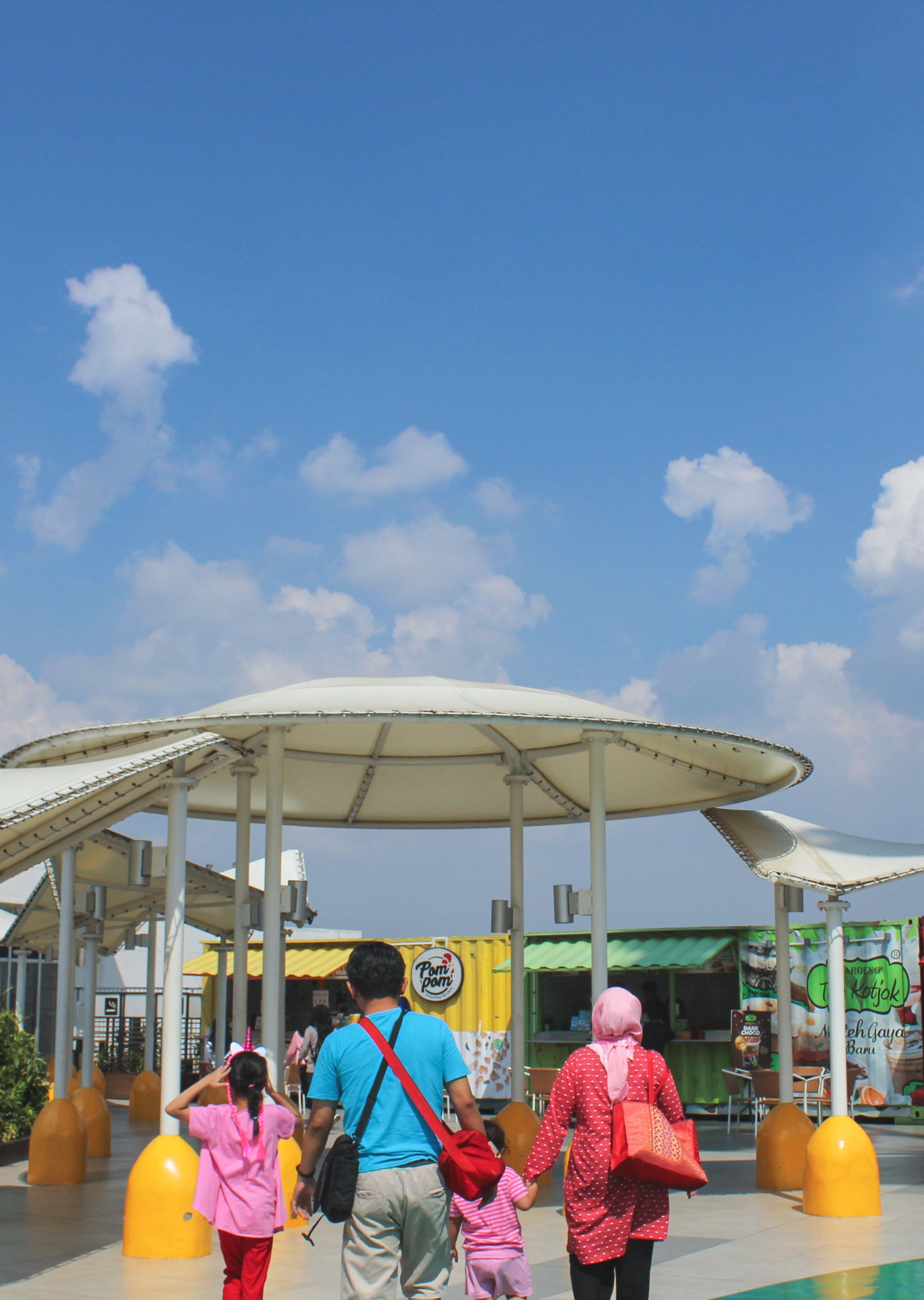 A family explores an outdoor market together on a sunny day, creating a vibrant, harmonious scene.