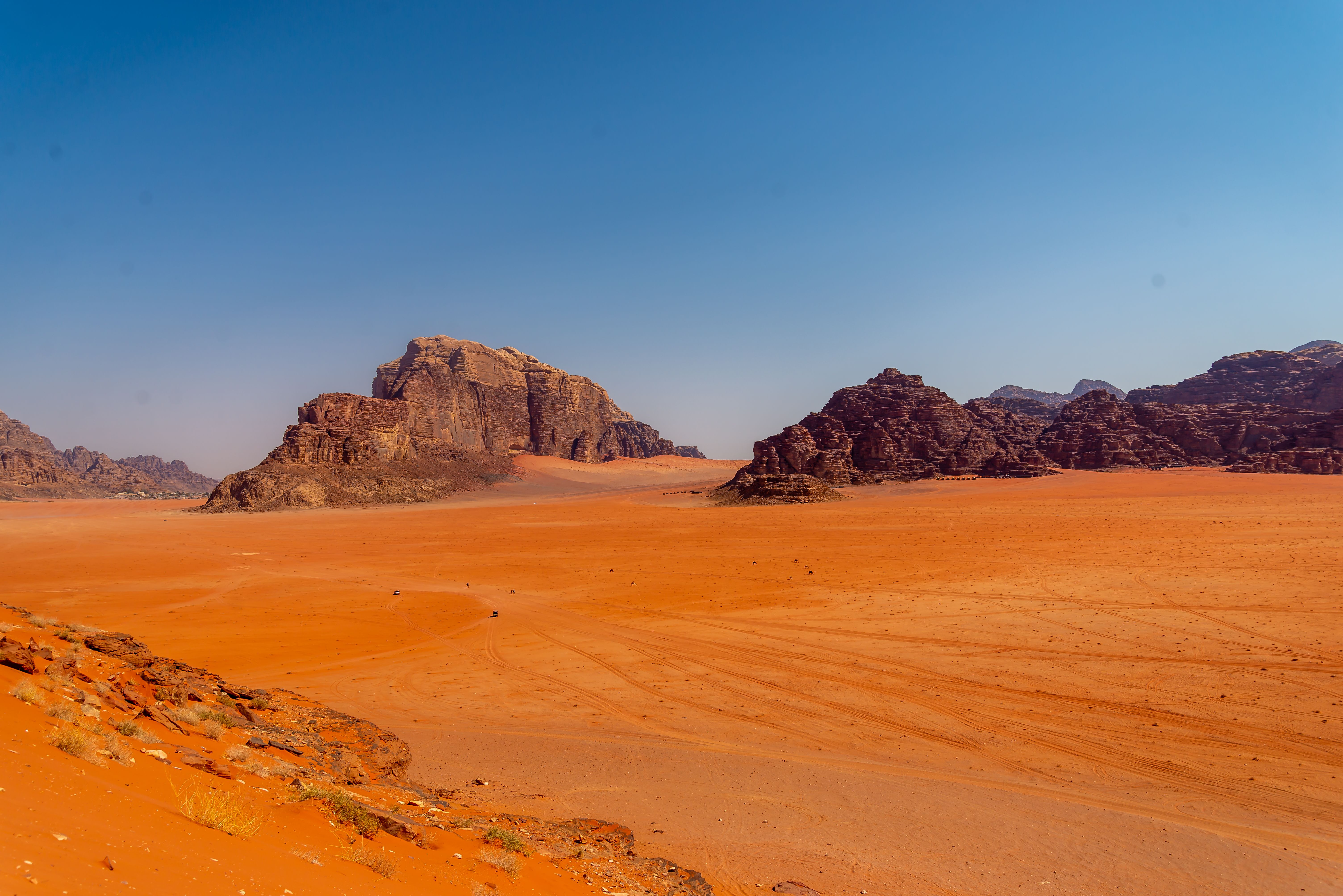 Red desert floor meeting towering rock formations in Wadi Rum