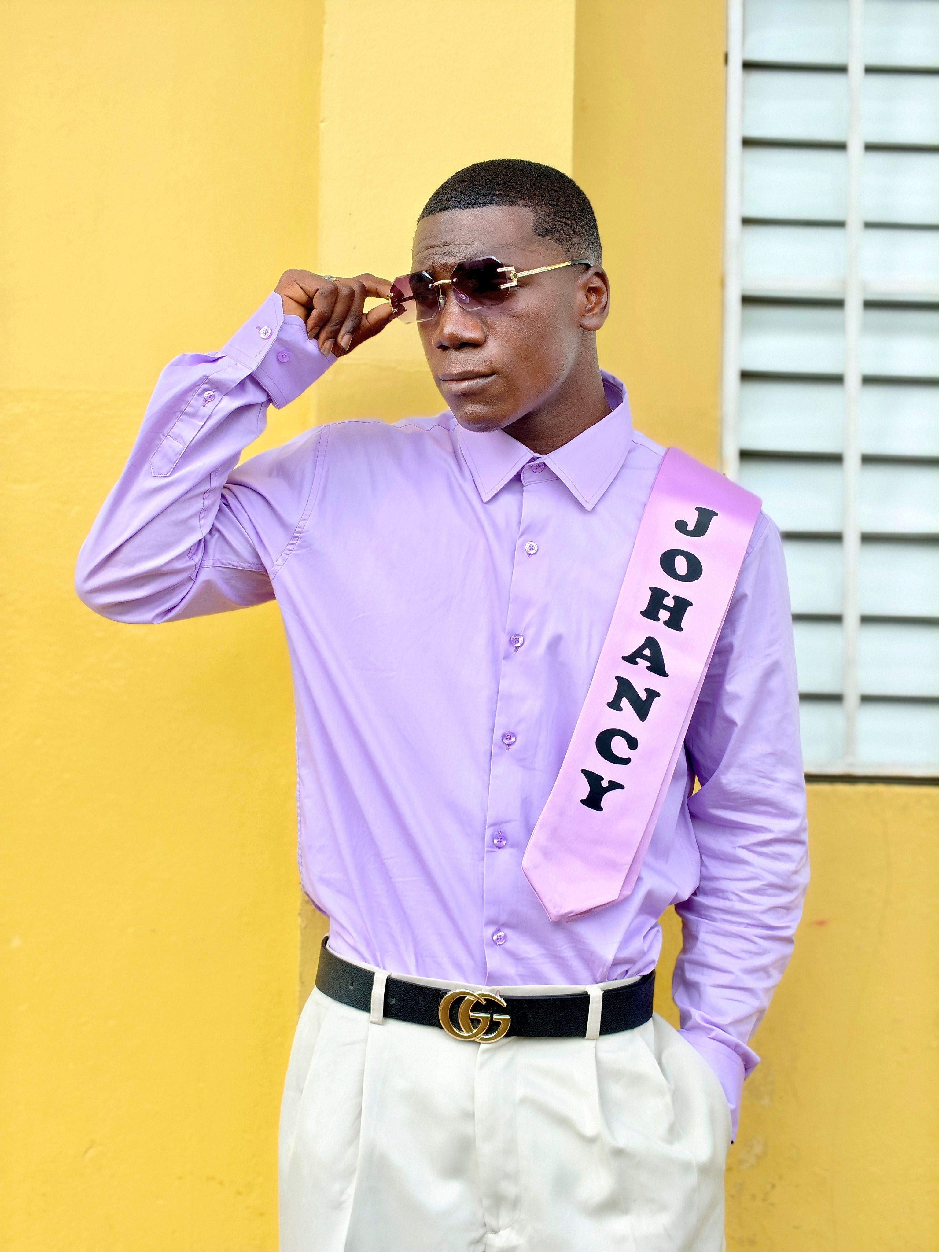 Stylish young man wearing sunglasses and a lavender shirt with a personalized sash.
