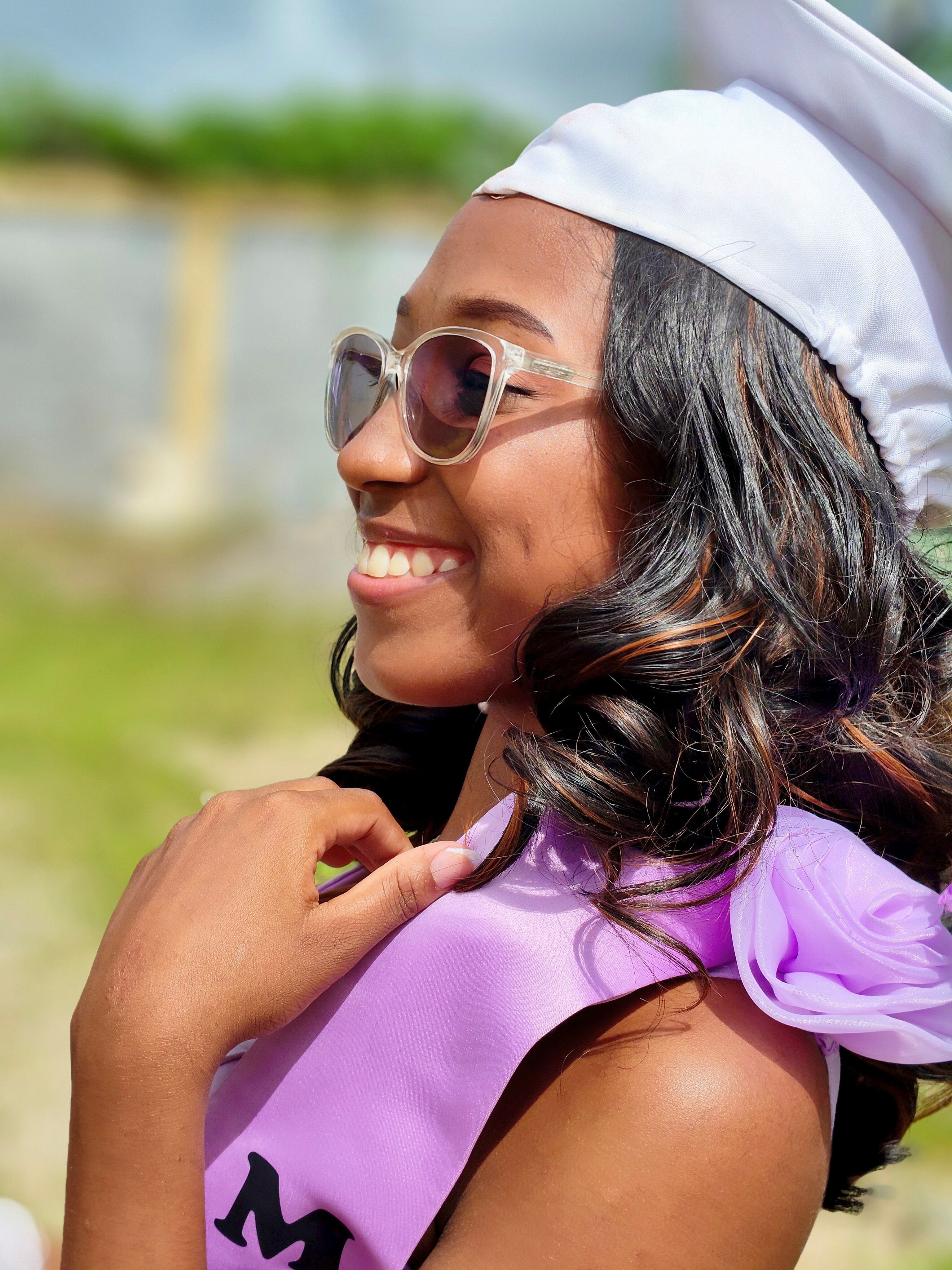 Joyful graduate in a cap and gown celebrates milestone achievement outdoors.