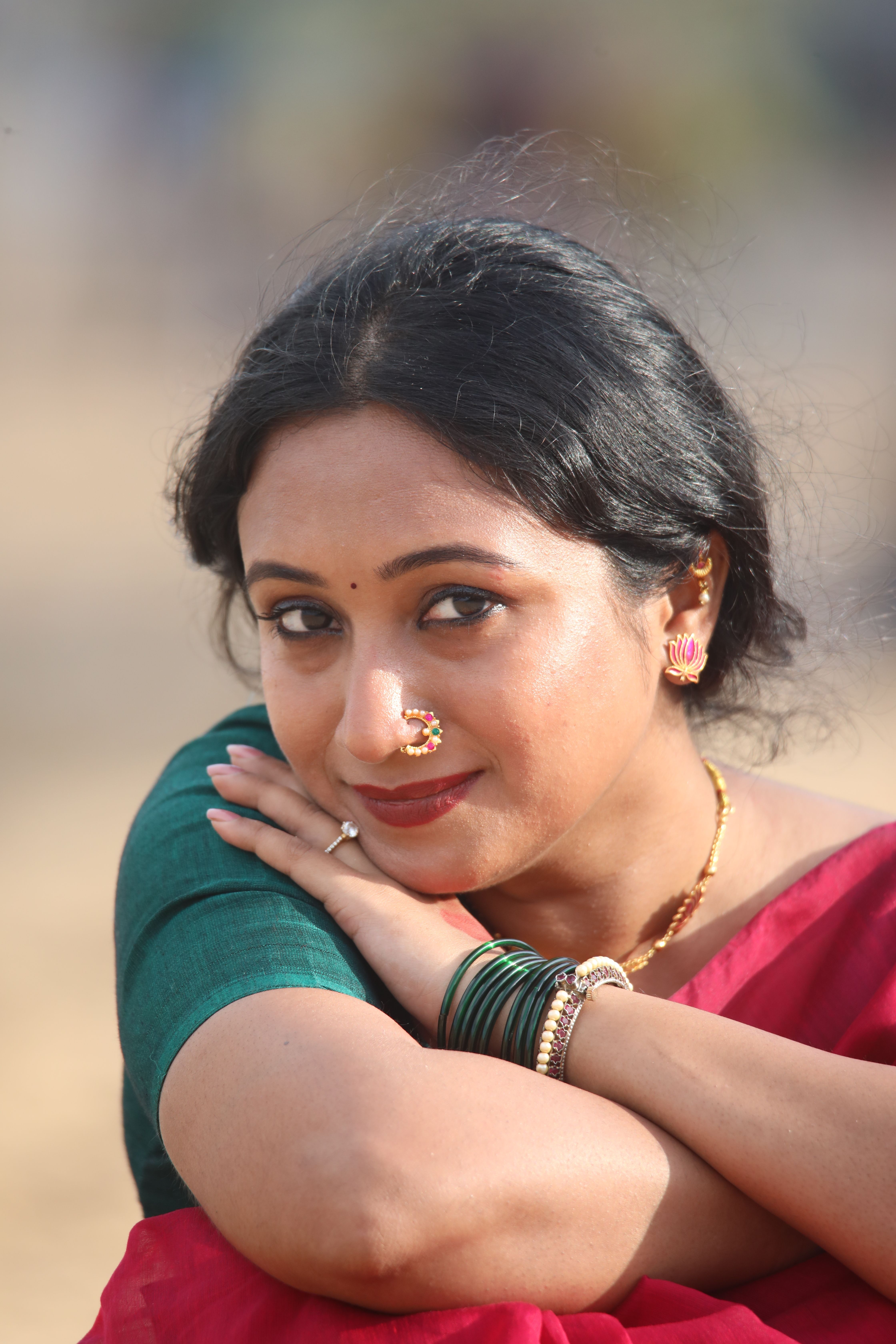 A serene portrait of a woman in colorful traditional attire outdoors.