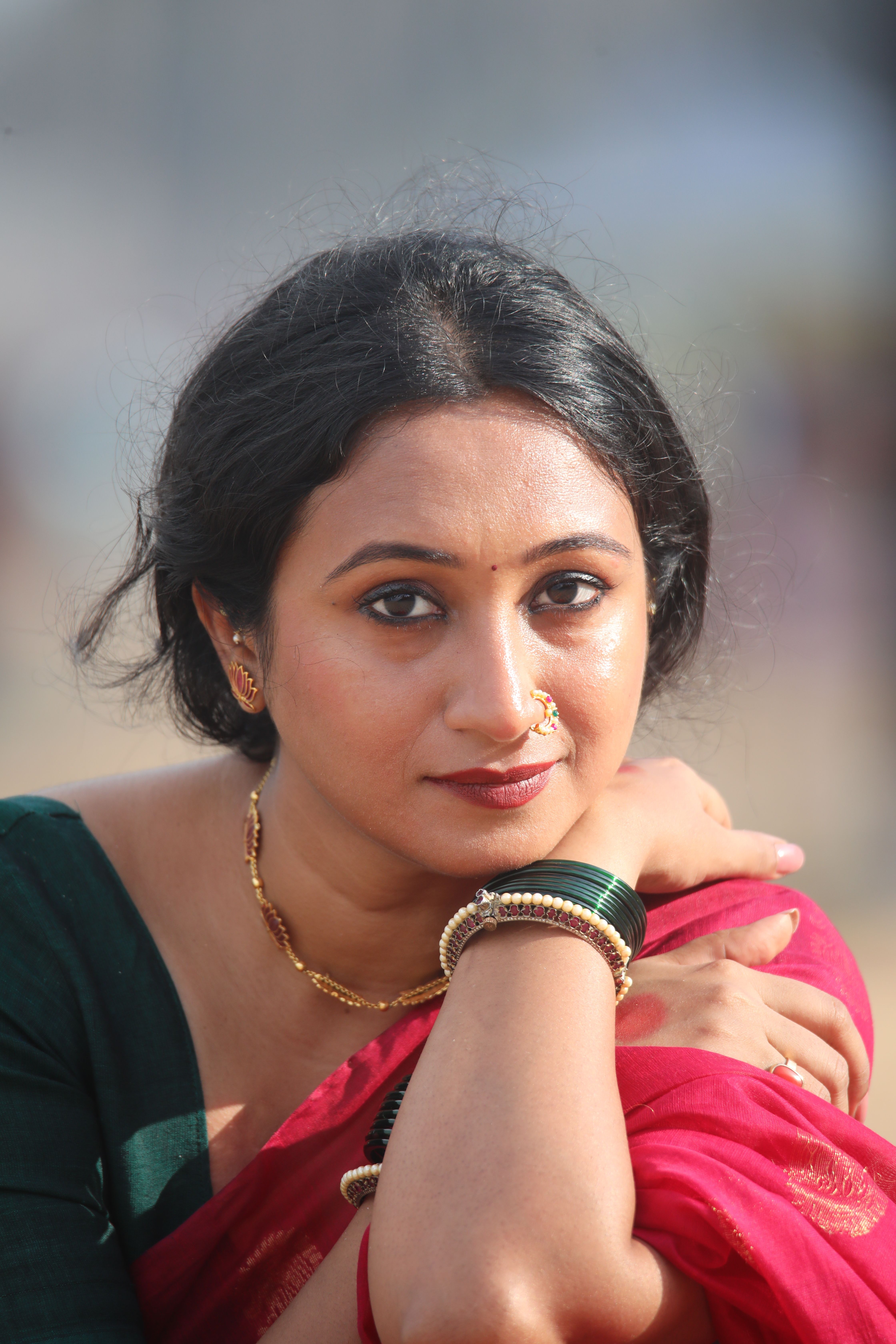 A close-up outdoor portrait of a woman in traditional attire displaying cultural jewelry.