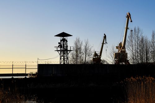 Free Serene sunset over an industrial harbor in Loksa, showcasing cranes and a tranquil maritime landscape. Stock Photo