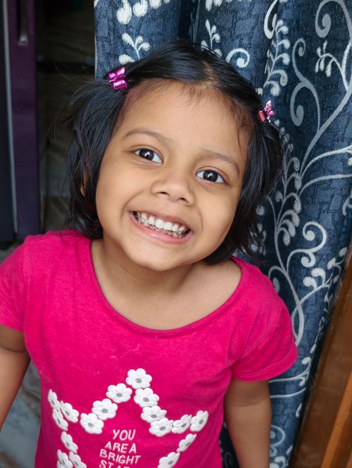 Free Cheerful young girl smiling brightly indoors with pink outfit. Stock Photo