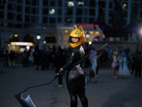 A cosplayer in a unique black suit and yellow helmet poses at a night event in Vietnam.