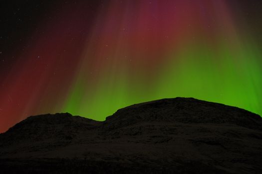 Nordlicht über dunkler Berglandschaft