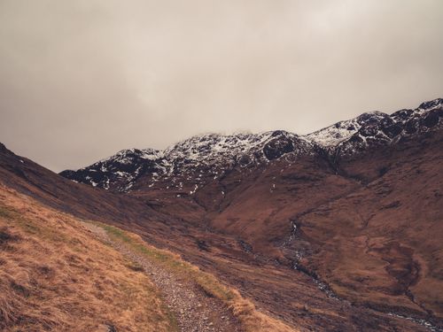 Free Majestic snow-capped mountains under overcast skies in early spring, Scotland. Stock Photo