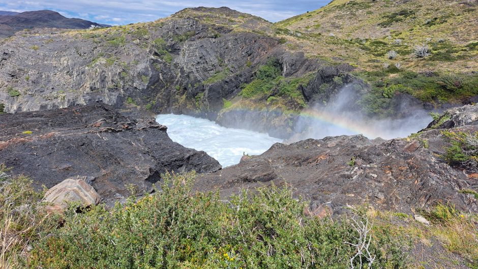 Vibrant waterfall with a rainbow in Magalhães, Chilean wilderness.
