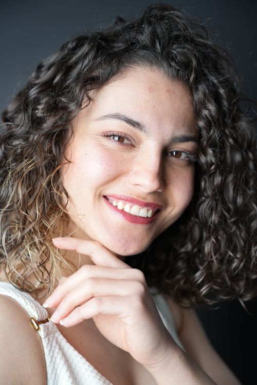 Free Close-up portrait of a smiling woman with curly hair, exuding joy and confidence. Stock Photo