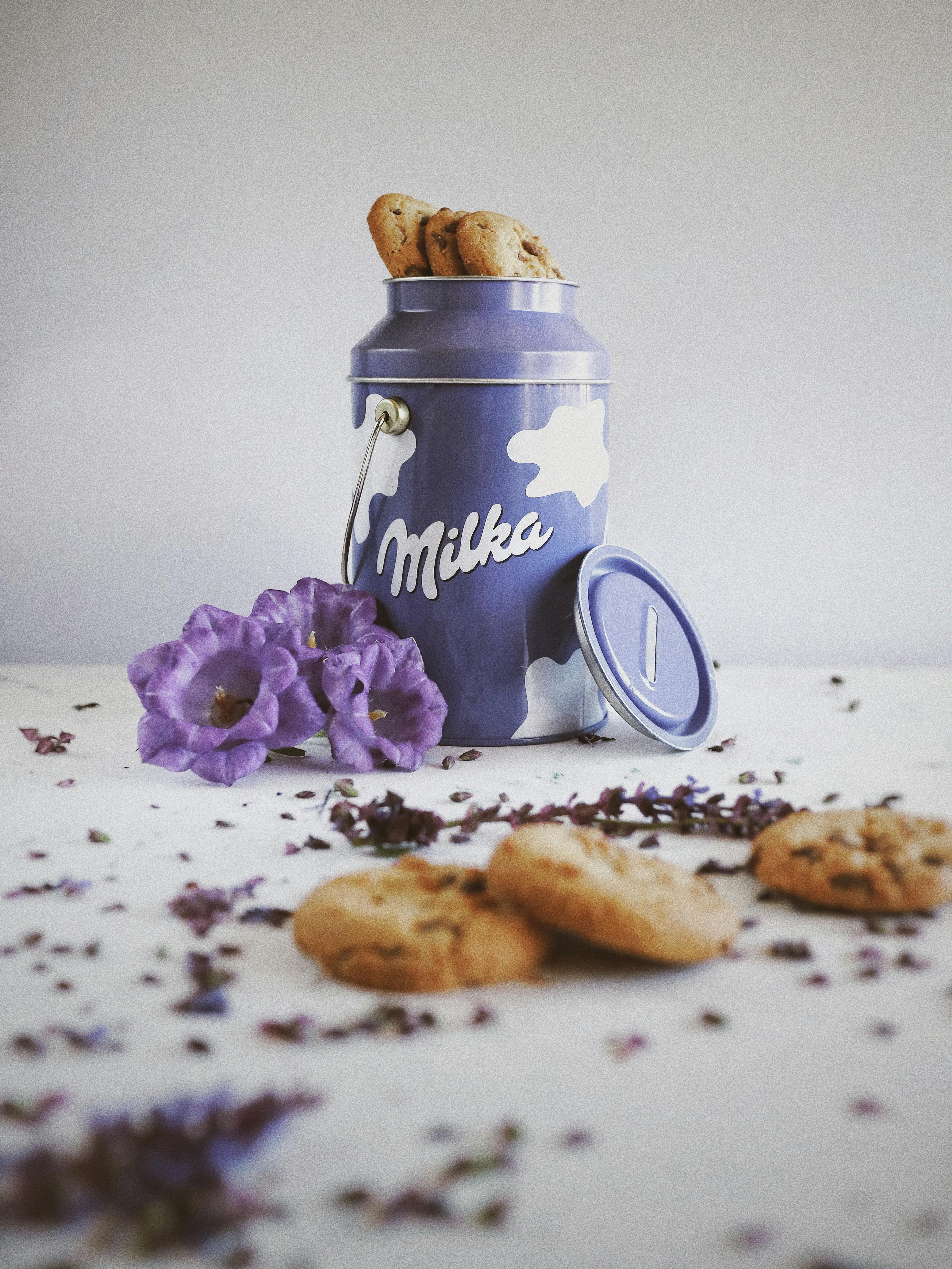 purple and white ceramic mug beside cookies on white ceramic plate