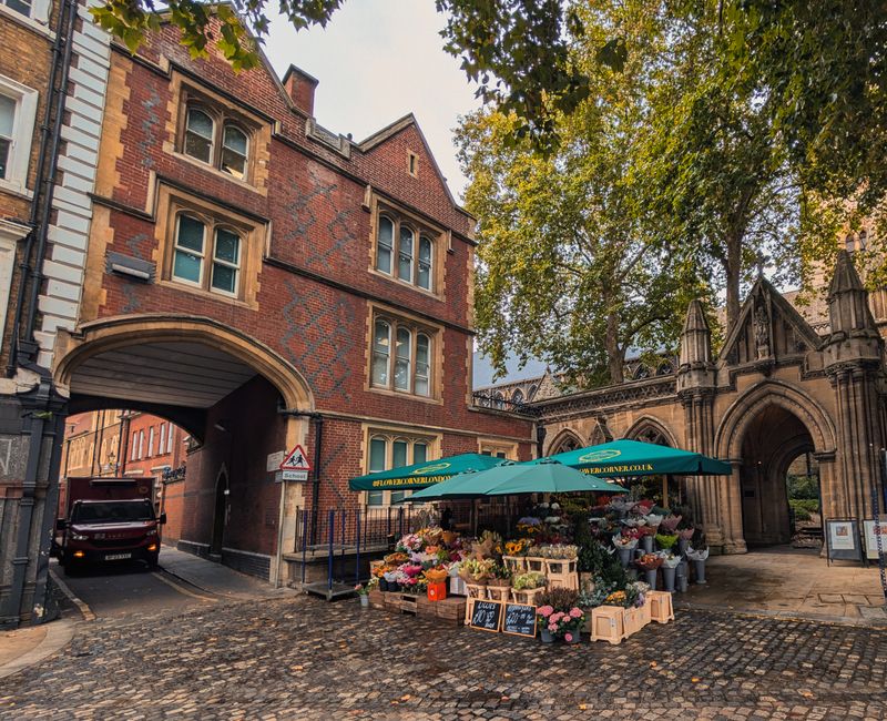 Explore a delightful flower market set amidst classic Gothic architecture in London, highlighting a street scene full of vibrant blooms.