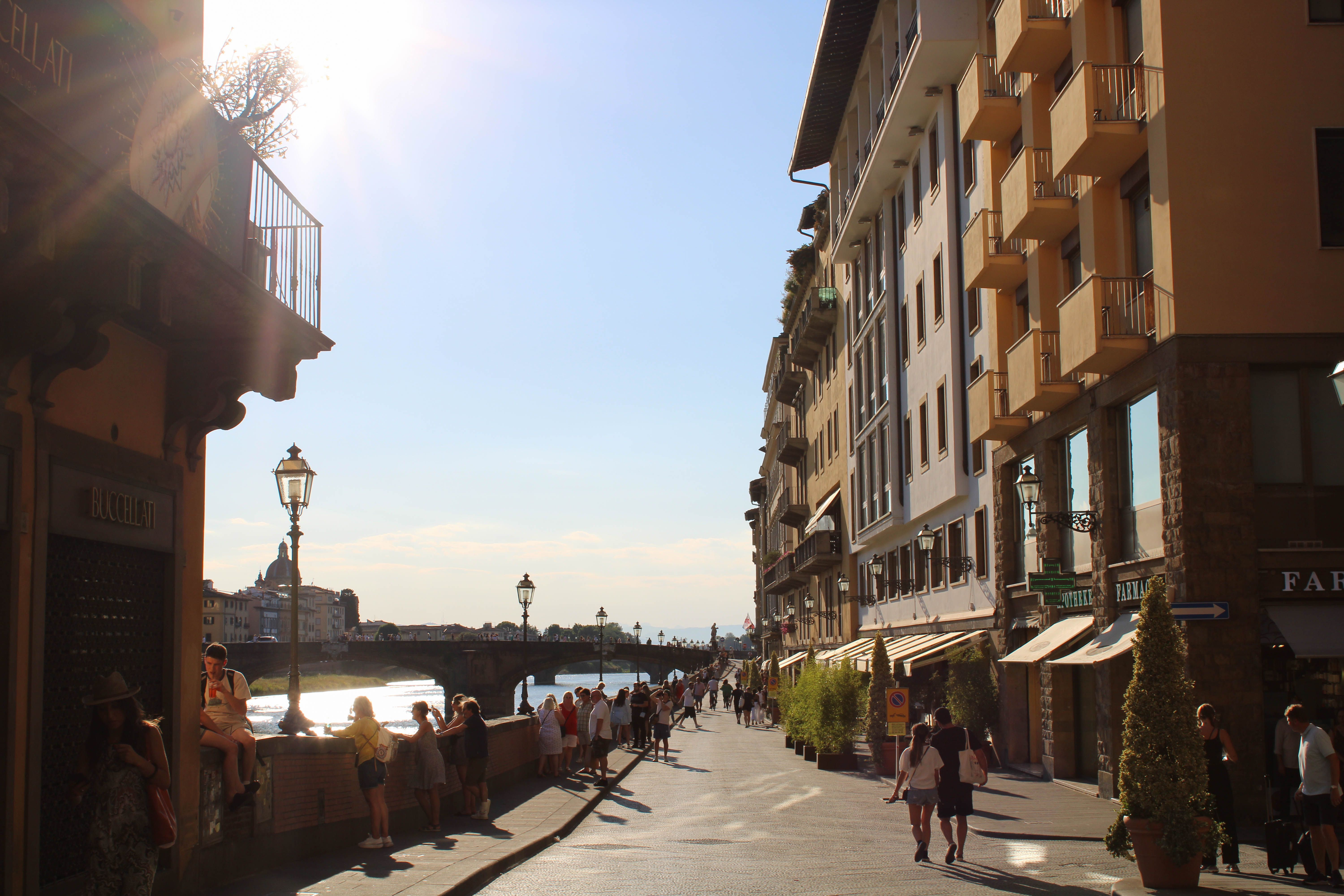 Sunlit street in Florence, capturing the essence of a summer day with people strolling by.