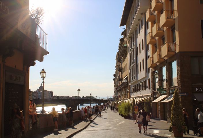 Sunlit street in Florence, capturing the essence of a summer day with people strolling by.