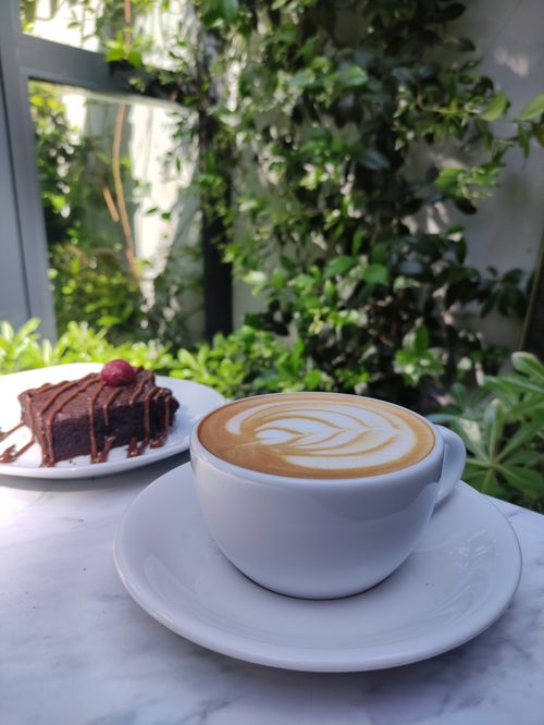 Free Enjoy a warm café latte and chocolate cake in a lush garden café setting in Bursa, Türkiye. Stock Photo