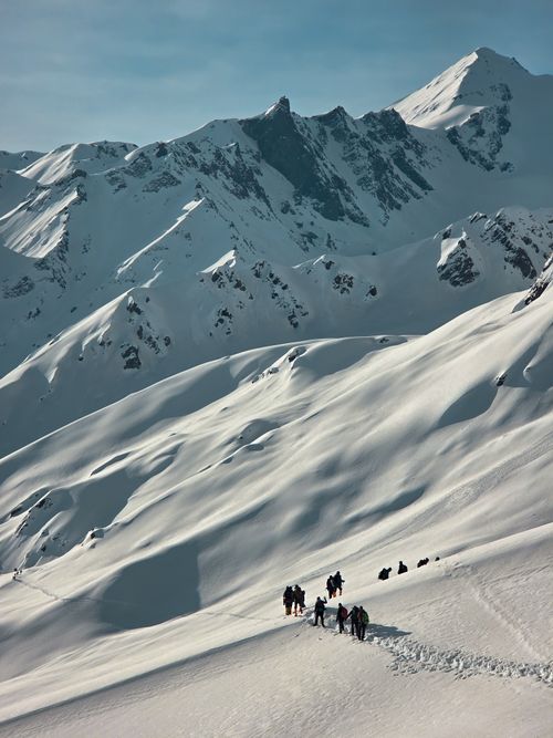 Free Adventurers trekking through snow-covered mountains in Kasol, India, surrounded by towering Himalayan peaks. Stock Photo
