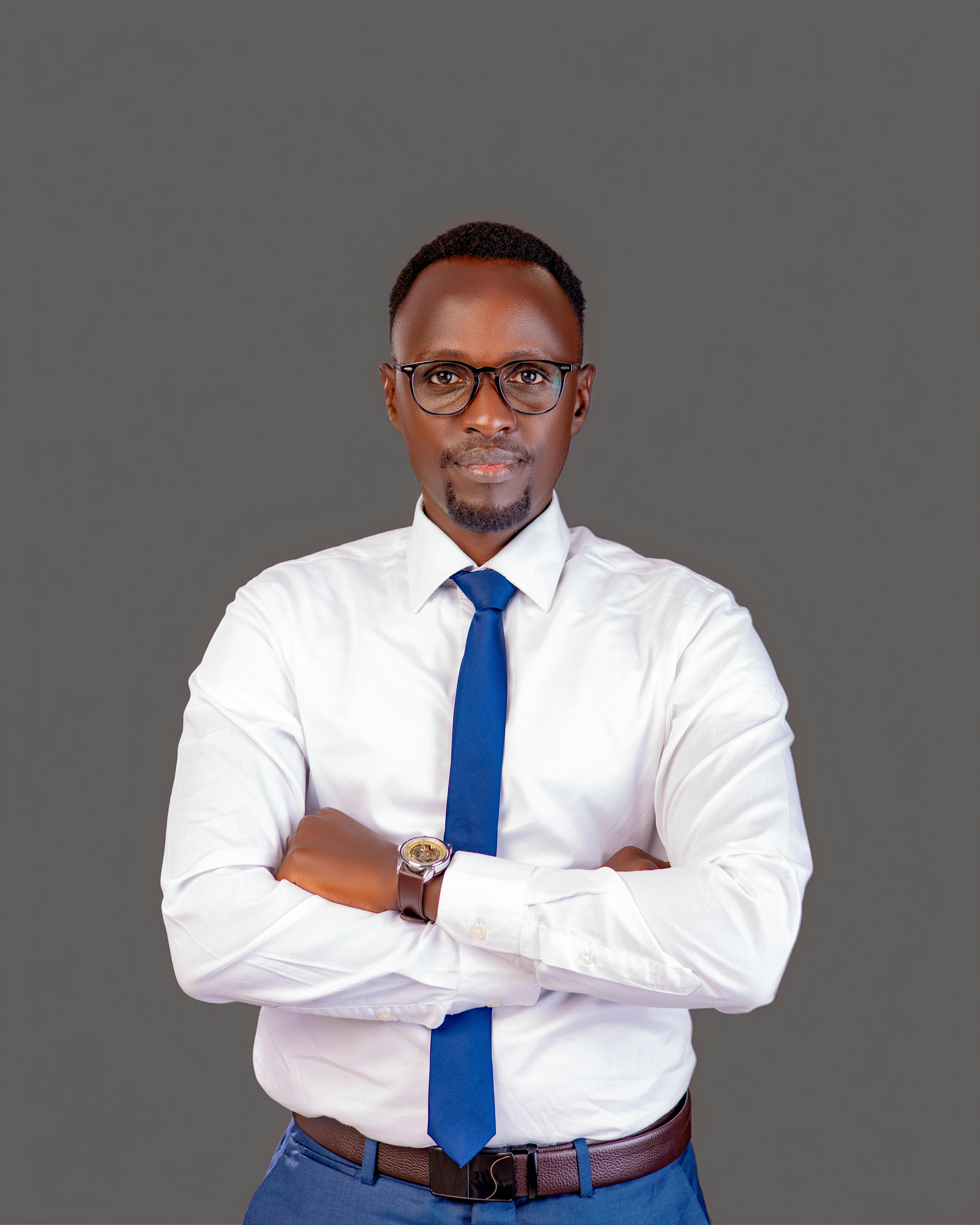 Portrait of a confident businessman in a white shirt and blue tie, standing against a neutral background.