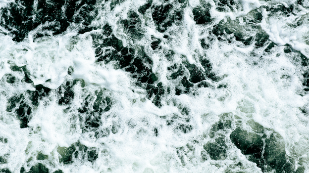 Aerial view of turbulent ocean waves with frothy white foam. Nature's power captured in motion.