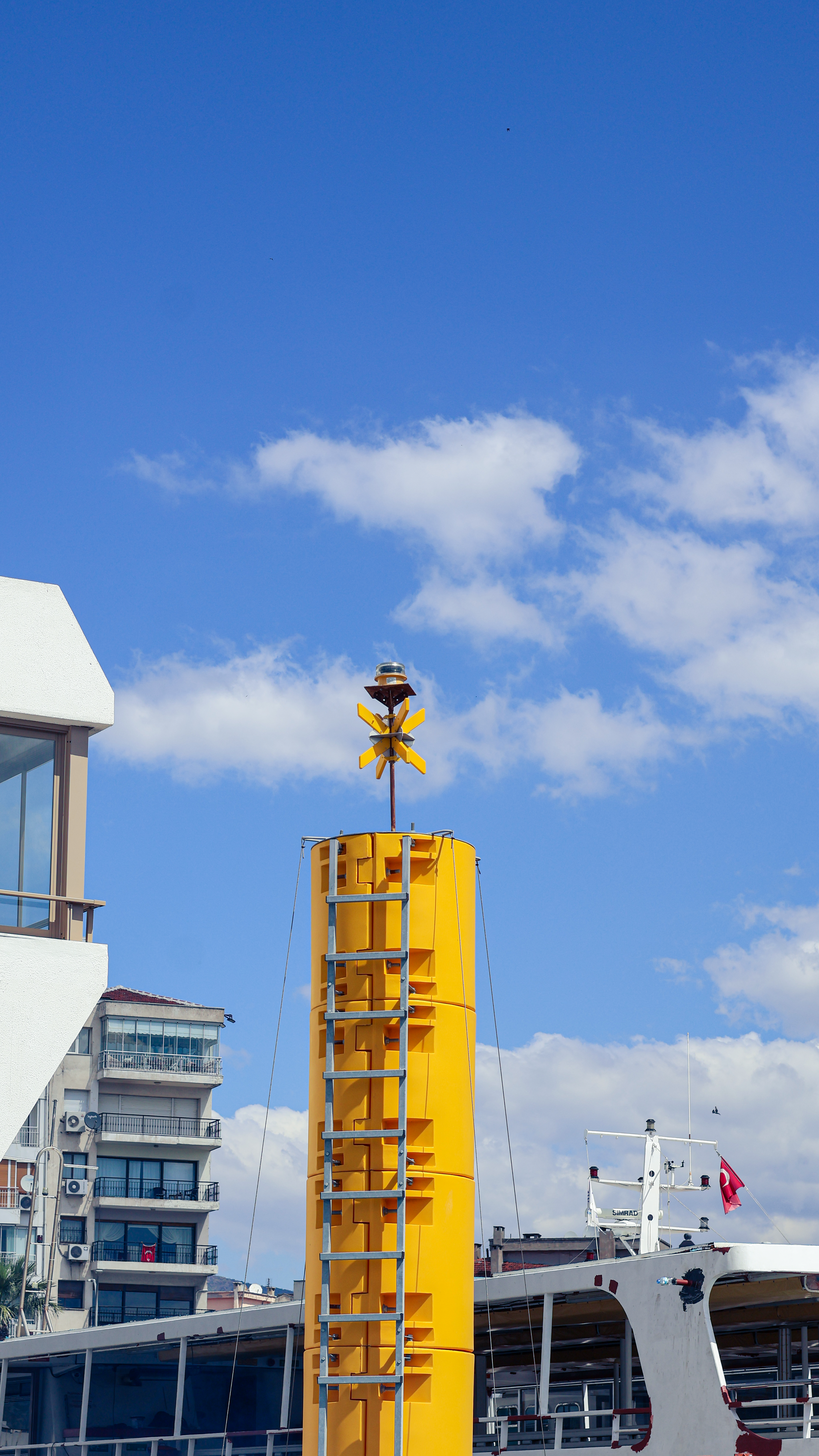 Yellow tower against clear blue sky with urban buildings.