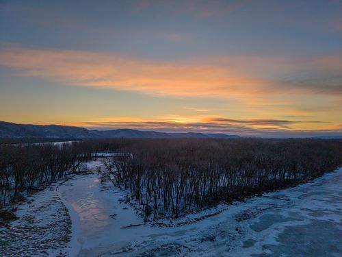Free A serene winter sunset over a frozen river and snowy landscape in West Newton, Minnesota. Stock Photo