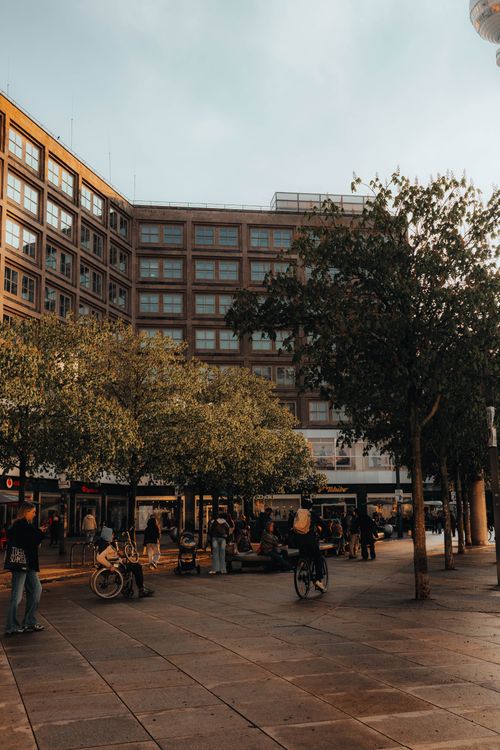 Free People enjoying a sunny afternoon in a Berlin city square surrounded by trees and buildings. Stock Photo