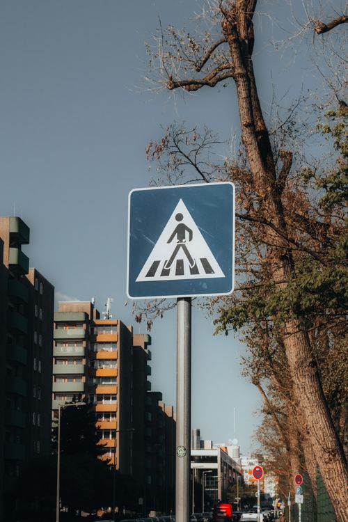 Free A pedestrian crossing sign amidst trees and buildings in Berlin, Germany. Stock Photo