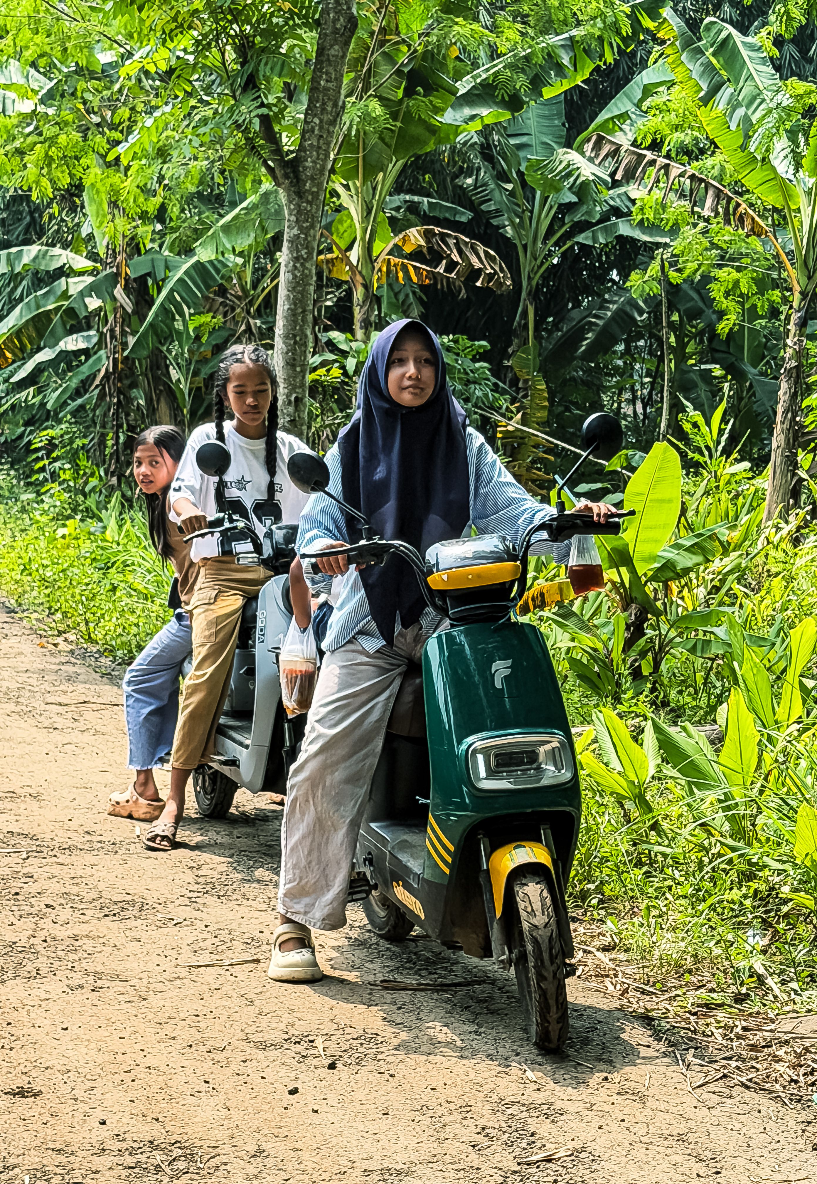 Young Women Riding Scooters through Lush Jungle Path · Free Stock Photo
