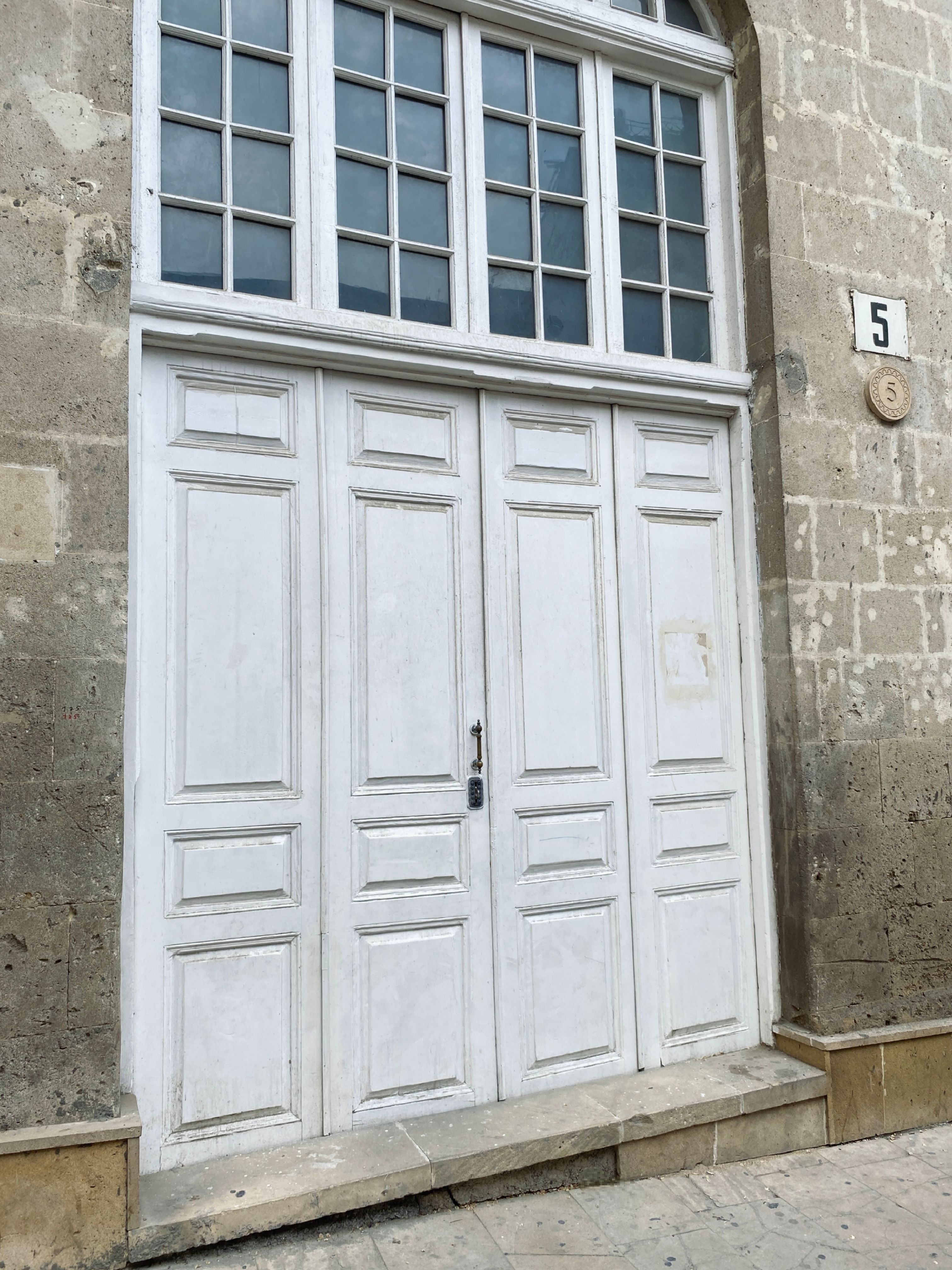 Elegant white wooden door set in a stone facade with grille windows in Baku, Azerbaijan.