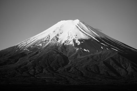Striking black and white photograph of Mount Fuji with snow-capped peak against clear sky.
