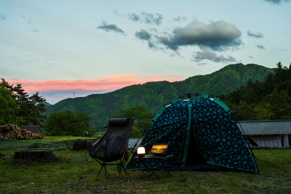 美しい山の夕日を背景にしたテント、椅子、ランタンを備えた静かなキャンプセッティング。