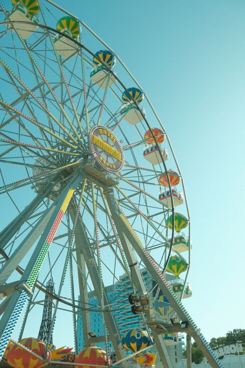 Free A vibrant Ferris wheel towering under a clear blue sky, perfect for a fun day out. Stock Photo