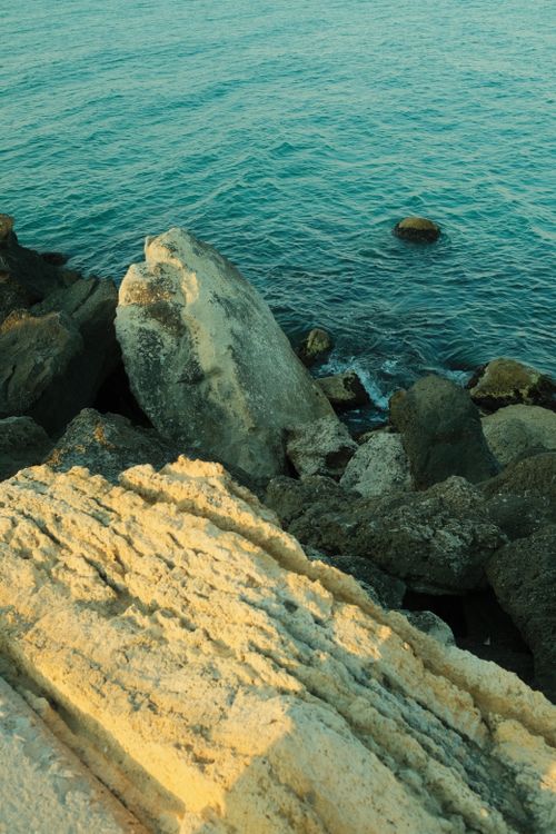 Free Serene coastal rocks against the vibrant turquoise sea, capturing nature's tranquility. Stock Photo