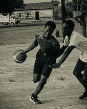 Two men engaged in a competitive basketball match on an outdoor court in Lagos, Nigeria.