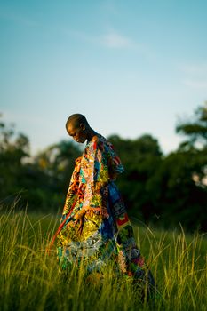 Captivating shot of a person in colorful traditional attire walking through a lush Ugandan field.