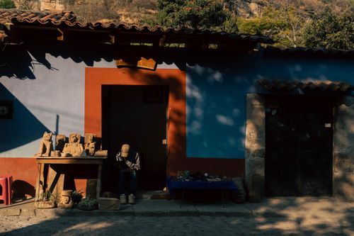 Free A quaint village scene with a craftsman in front of a colorful building lit by the setting sun. Stock Photo