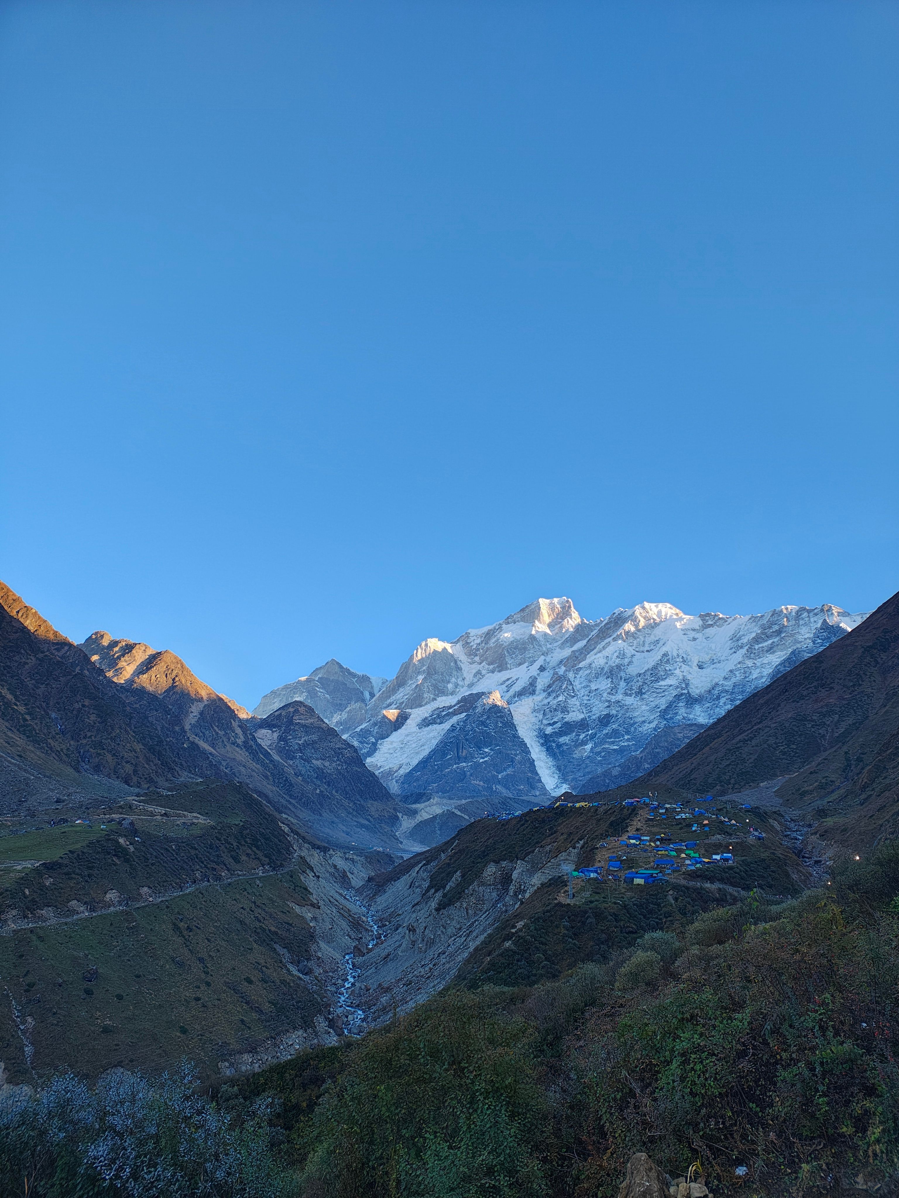 Breathtaking view of Kedarnath mountains with blue sky, capturing serene nature and remote landscape.