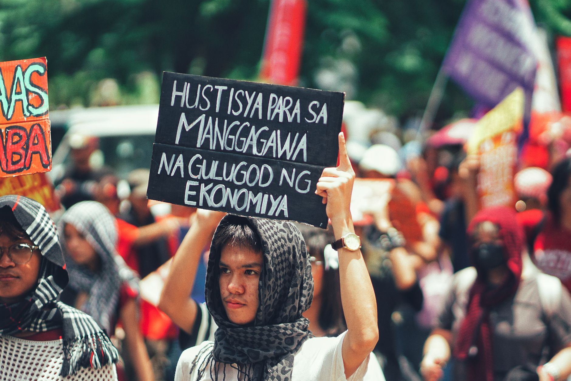 Protesters gathered outdoors holding signs demanding economic justice and workers' rights.