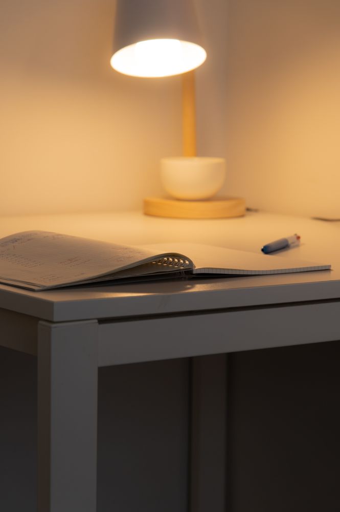 A warm, inviting desk with an open notebook, pen, and lamp — a gentle symbol of taking the first step toward support
