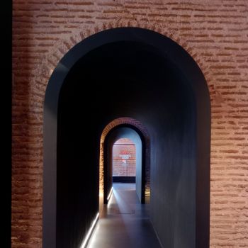 A beautifully lit brick archway corridor with a modern design showcasing depth and shadows.（イメージ）