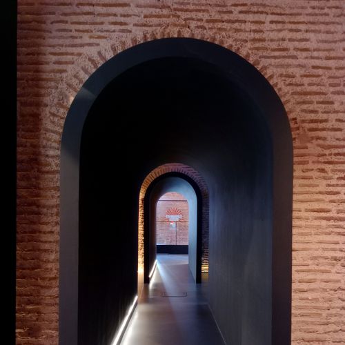 Free A beautifully lit brick archway corridor with a modern design showcasing depth and shadows. Stock Photo