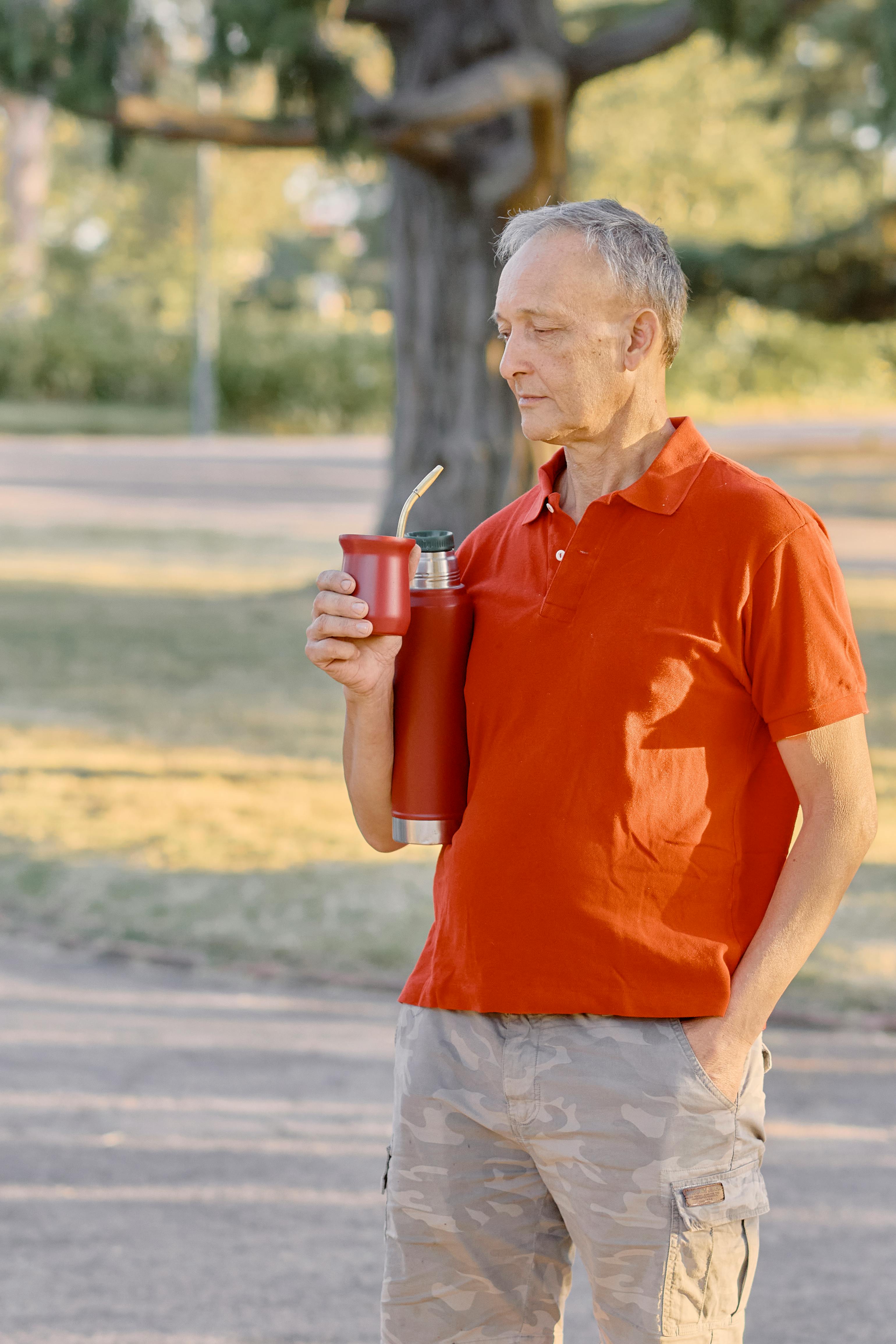 Senior man relaxing and drinking yerba mate outdoors in a tranquil park setting in Uruguay.