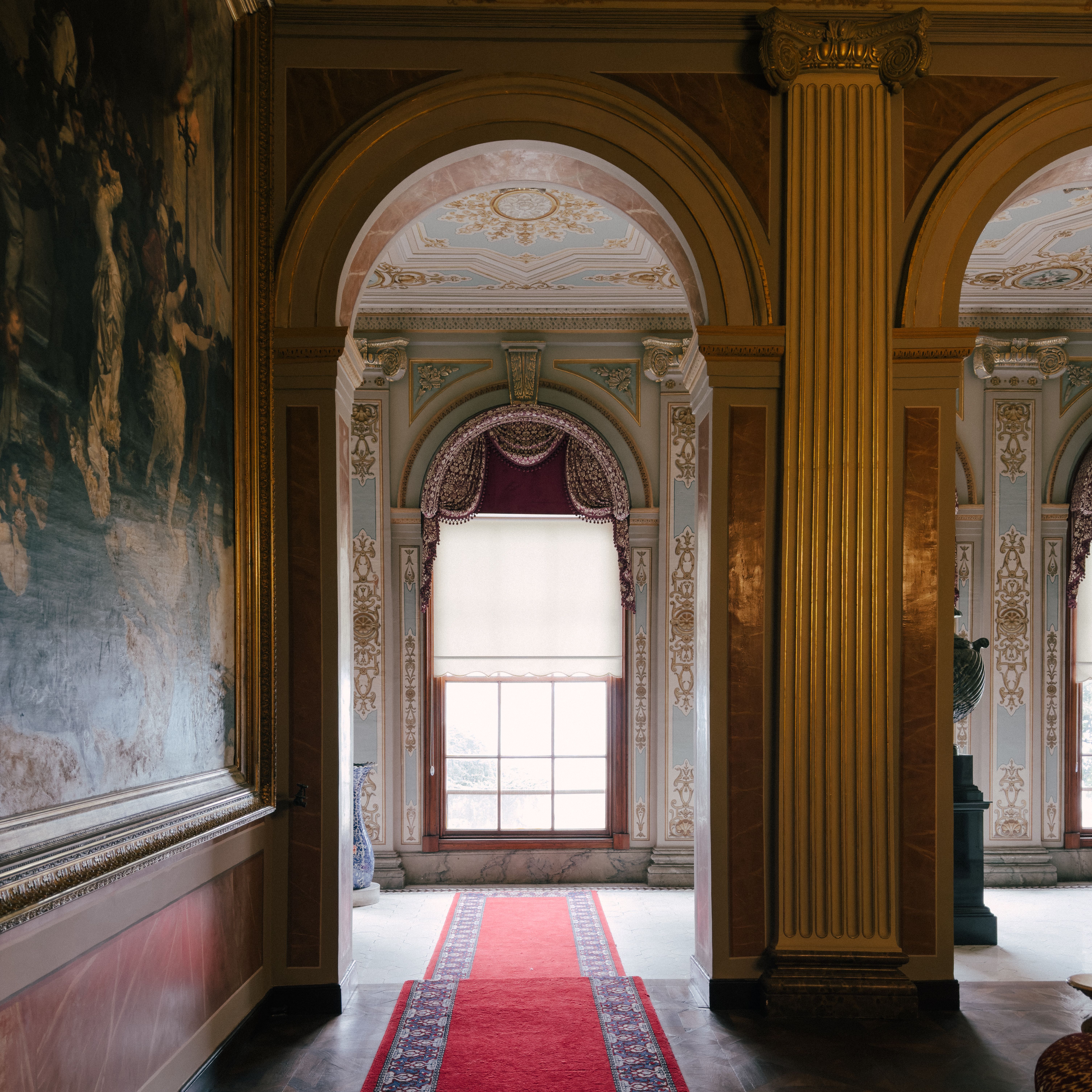 Luxurious interior featuring ornate arches, intricate ceiling, and a plush red carpet in a grand hallway.