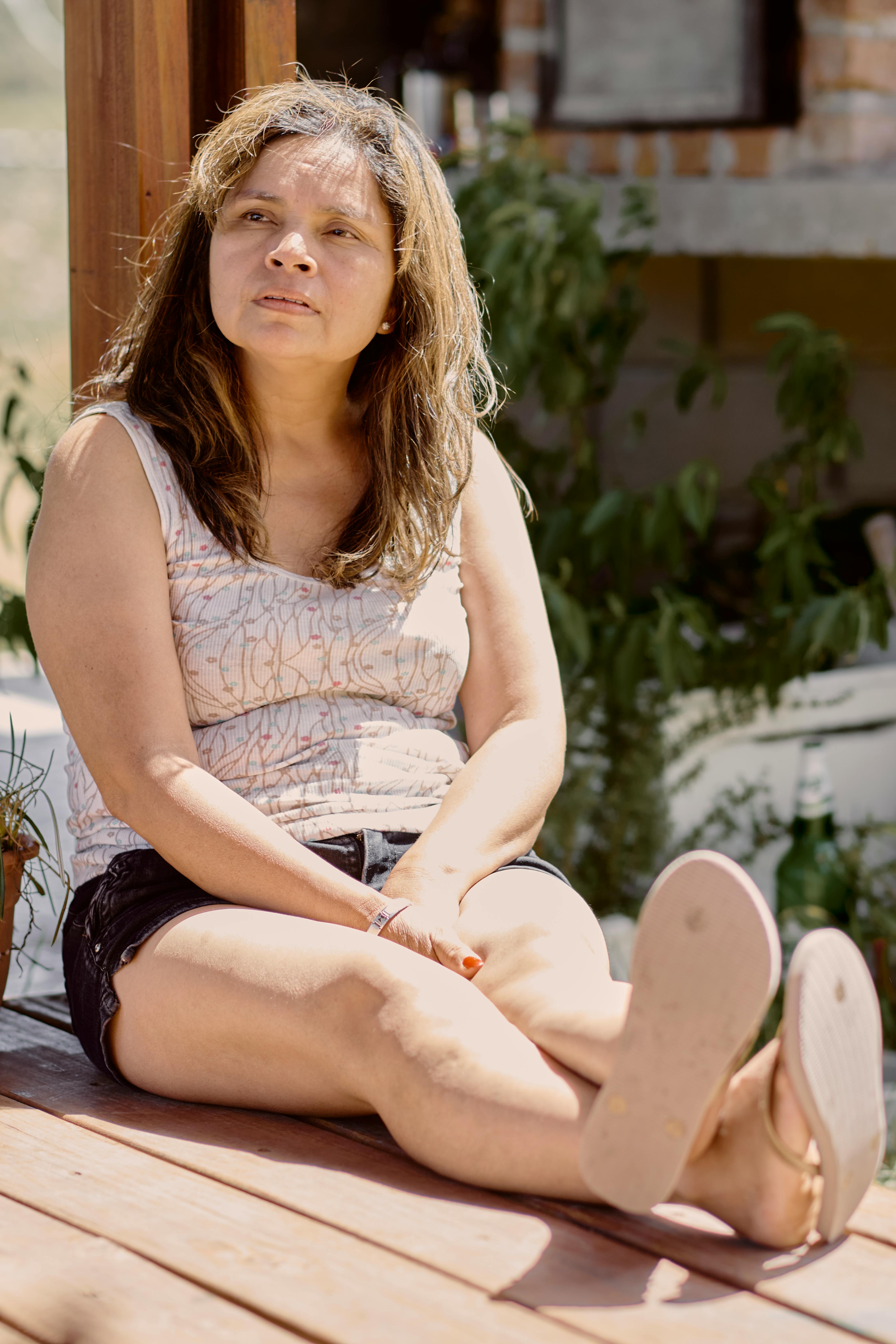 Woman sitting on deck in sunshine, enjoying a peaceful moment outdoors in Uruguay.