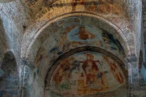 Free Detailed view of ancient frescoes adorning an old stone church's arched ceilings. Stock Photo