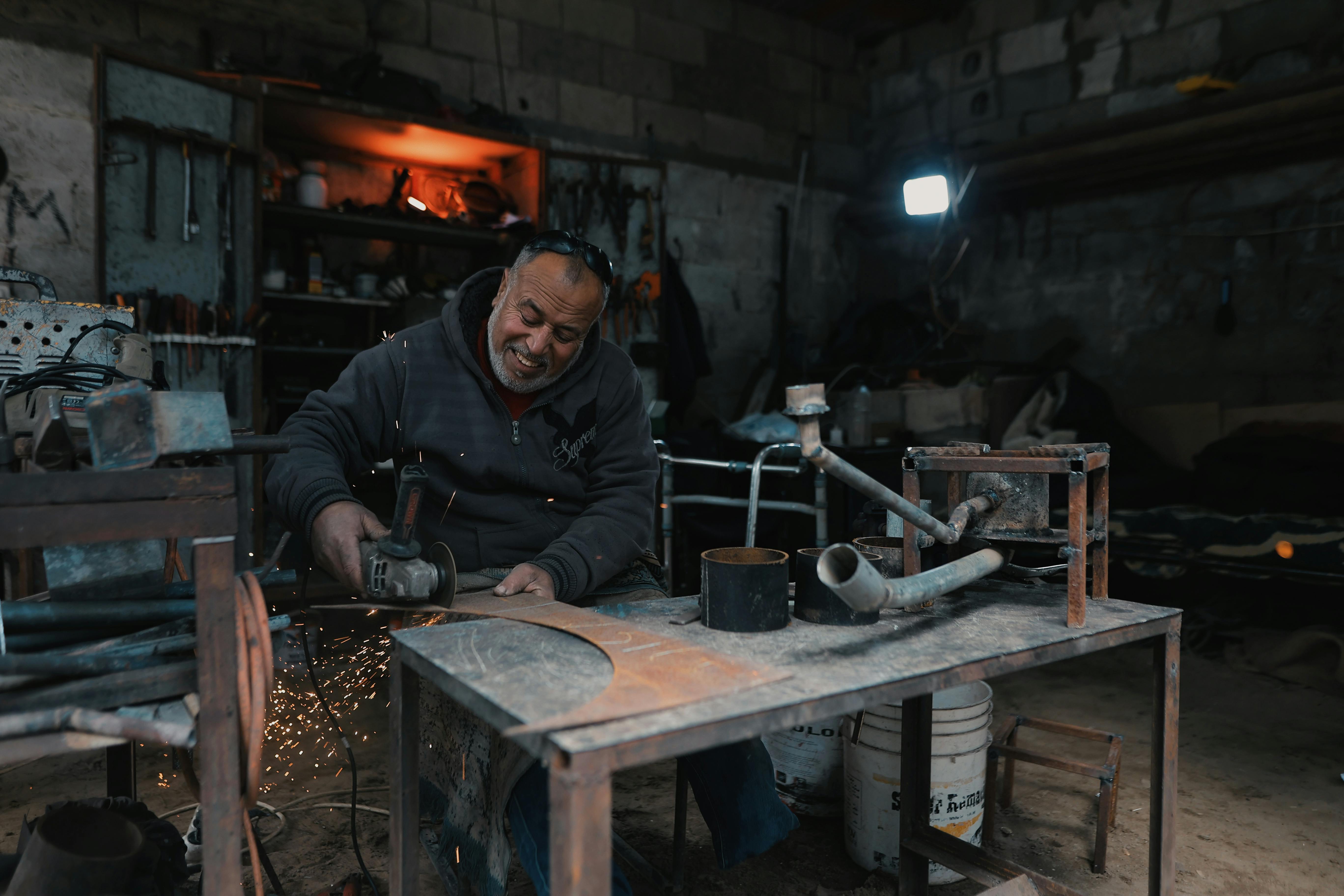 A craftsman skillfully grinds metal in a dimly-lit workshop, producing bright sparks.