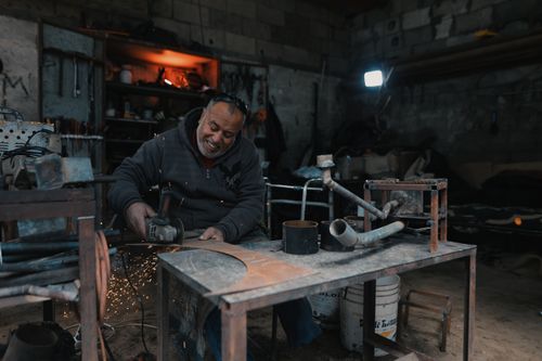 Free A craftsman skillfully grinds metal in a dimly-lit workshop, producing bright sparks. Stock Photo