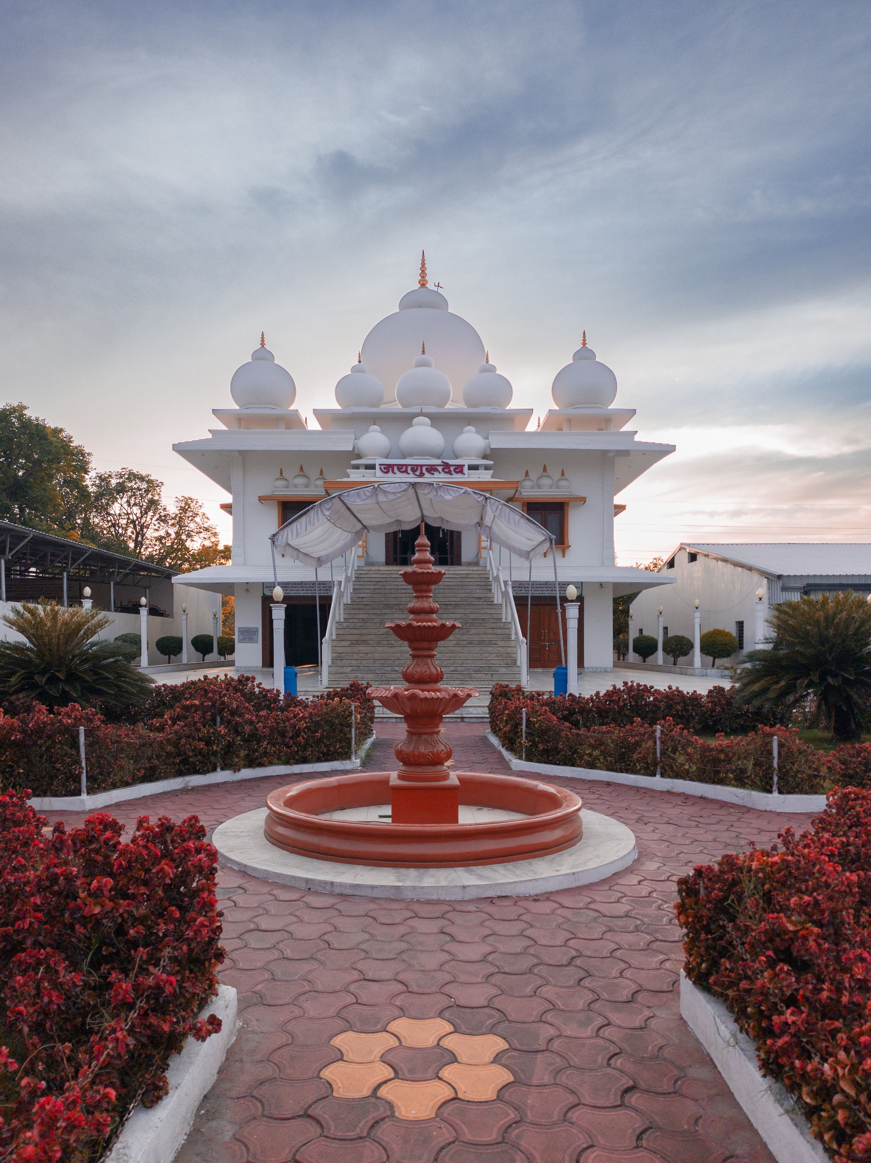 Beautiful temple in Mirjapur, Madhya Pradesh, India captured at sunset with vibrant red foliage in the foreground.