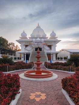 Beautiful temple in Mirjapur, Madhya Pradesh, India captured at sunset with vibrant red foliage in the foreground.