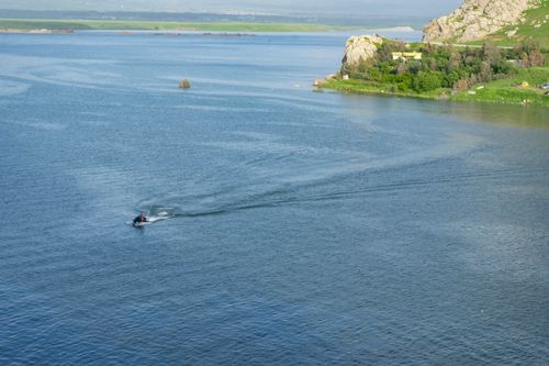 Free A tranquil lake scene in Iraqi Kurdistan featuring a jet ski under clear blue skies. Stock Photo