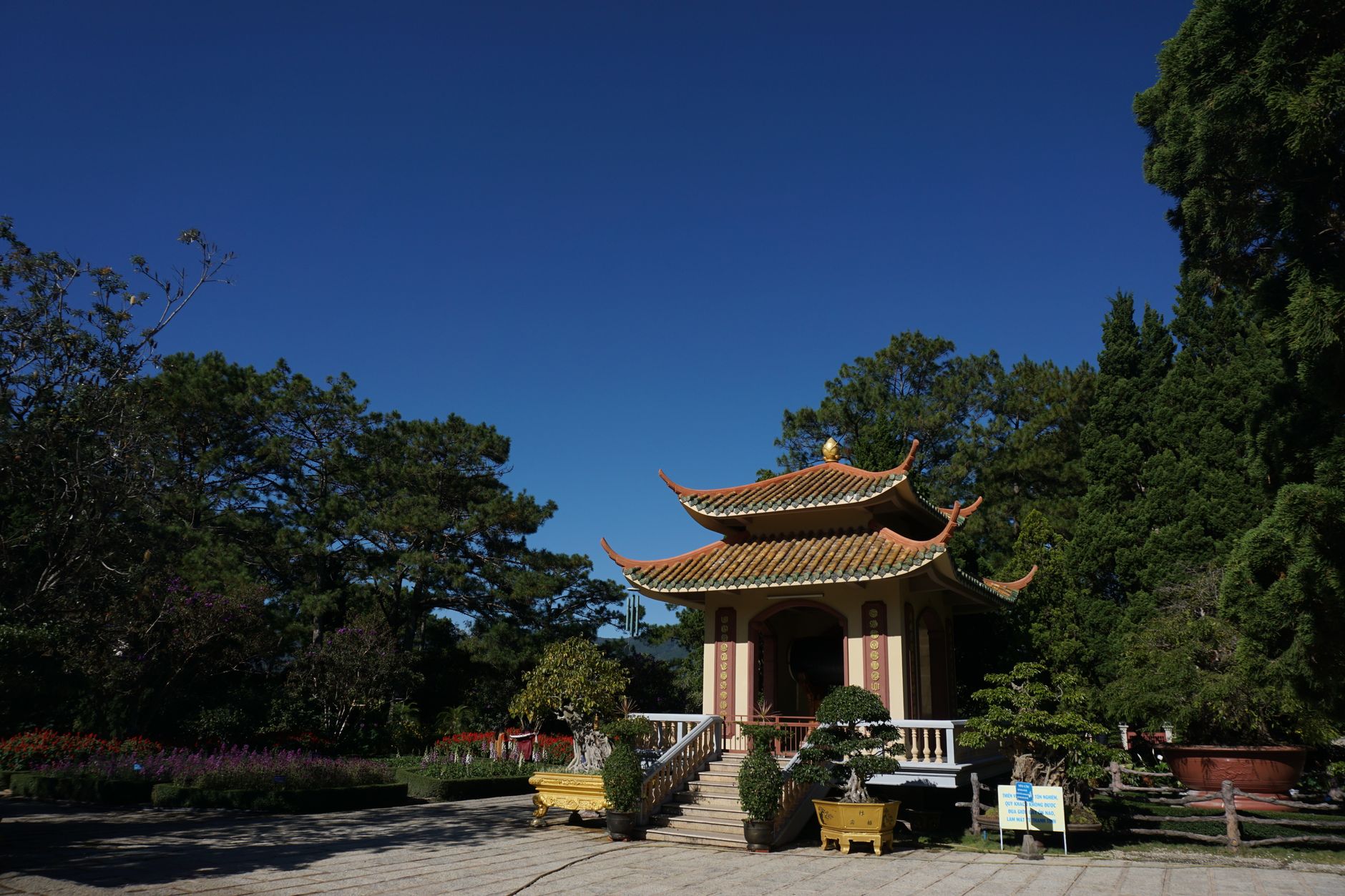 Traditional pagoda surrounded by lush greenery on a clear day in Đà Lạt, Vietnam.