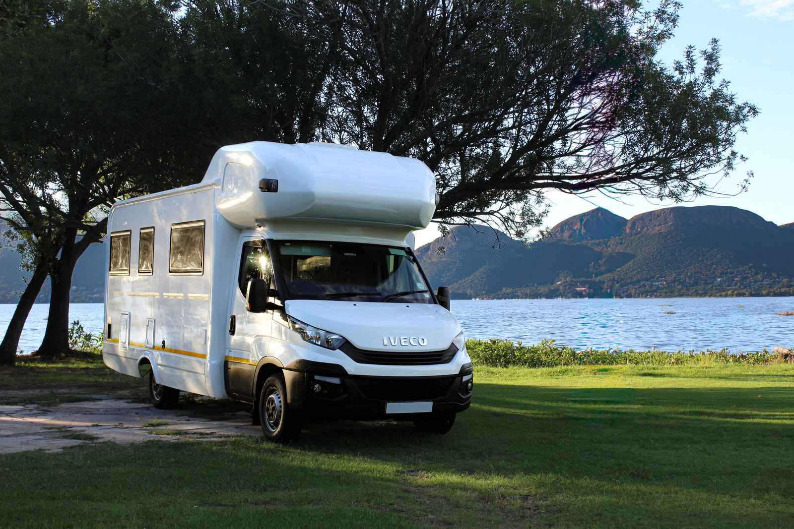 Modern motorhome parked lakeside beneath mountains